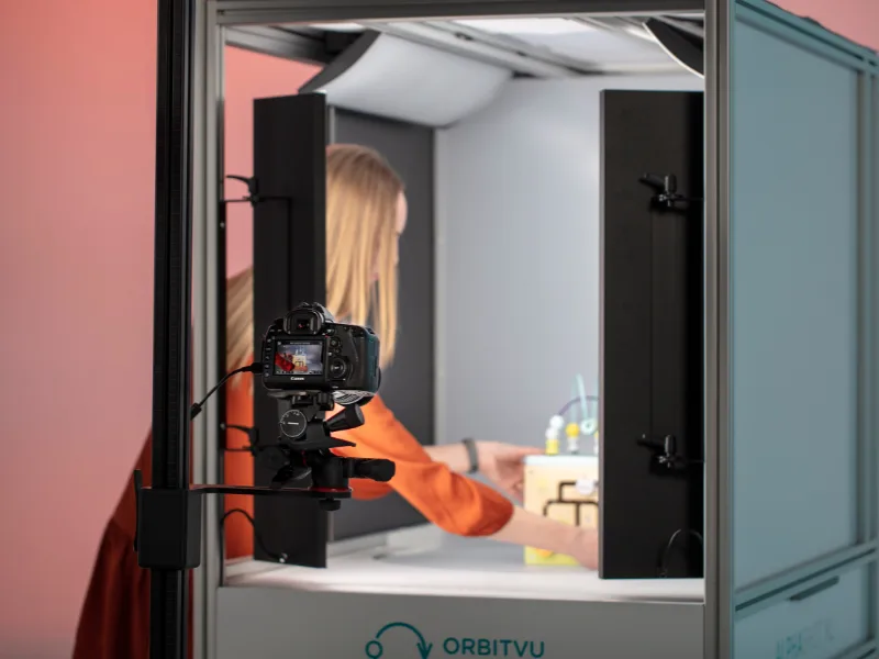 Operator placing a product inside Alphashot XL v2, camera and cables visible