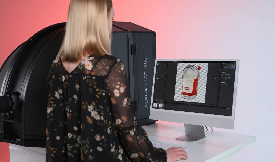 Operator reviewing a background-removed coffee maker image on screen next to the Alphashot 360 G2 studio